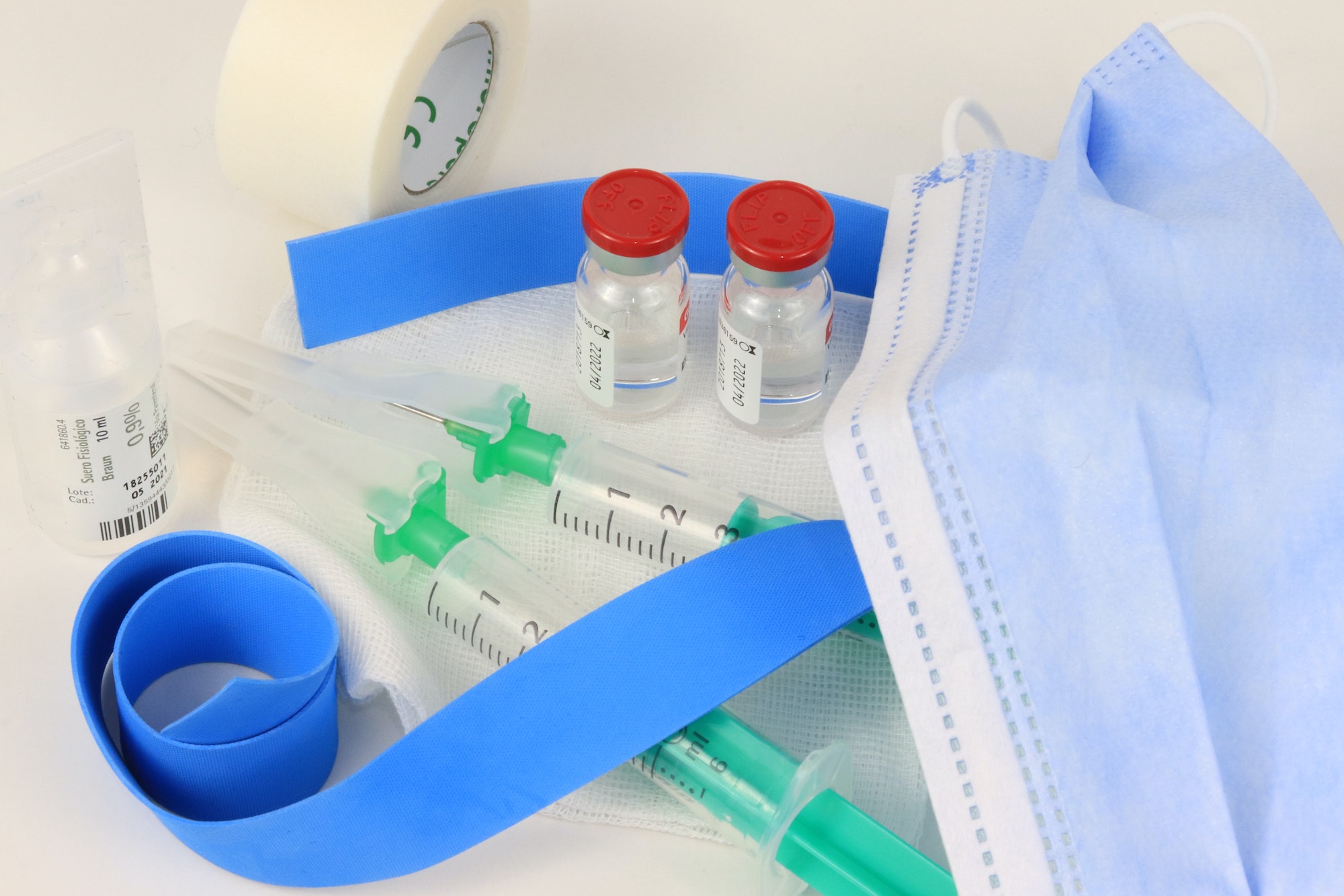 Shot of vaccine containers, a tape, gloves, syringe and other medical products on a table